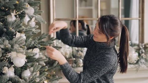 Woman Decorating Christmas Tree in Home
