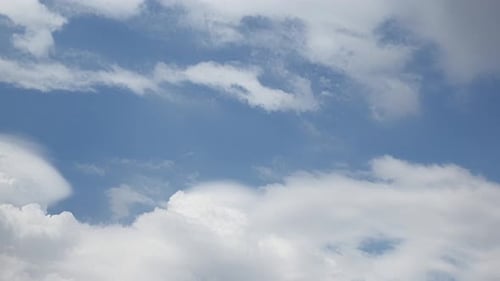 Fluffy White Clouds Moving Across a Blue Sky