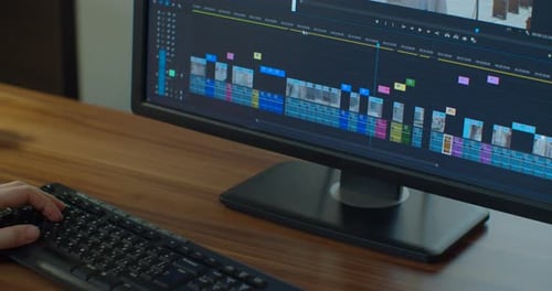 Nahaufnahme der Hände eines männlichen Videoredakteurs, während er an einem Schnitt für eine knappe Frist arbeitet und der Kunde in seinem