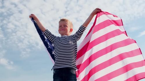 Young Boy Celebrates with American Flag in Blue Sky