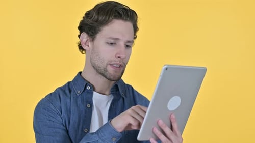 Joyeux jeune homme utilisant une tablette numérique sur fond jaune