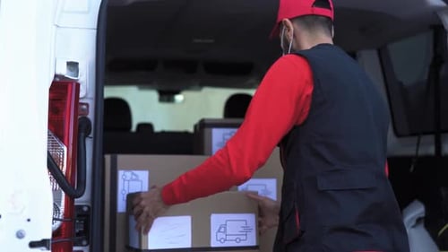 Der Zusteller lädt Kisten in den LKW, während er eine Gesichtsmaske trägt, um die Ausbreitung des Koronavirus zu vermeiden