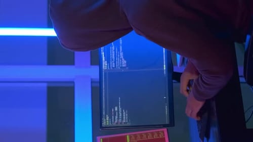 Back View of Hacker Dressed in a Dark Close Working on Computer