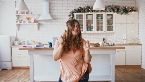 Woman Dances with Headphones in Bright Kitchen