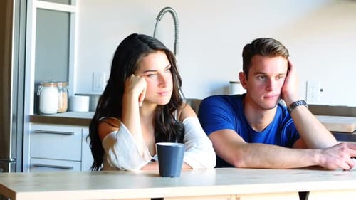 Couple Sitting Sadly at Table in Modern Kitchen