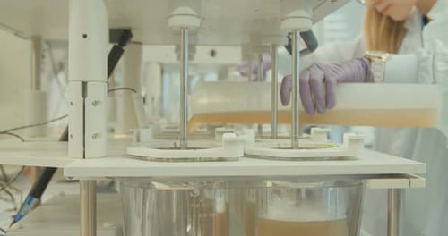 Woman Pours Liquid into Beaker During Lab Experiment
