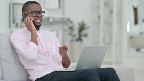 Man Talking on Phone with Laptop on Lap