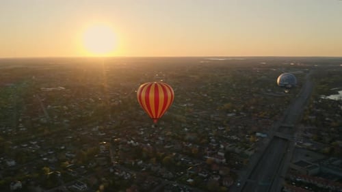 Hot Air Balloon Festival Floating Above City and Orange Skies During Sunset