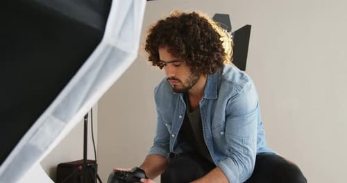 Photographer Looks at Digital Camera in Studio