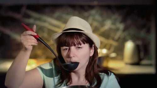 Woman Tastes Food in Kitchen with Ladle