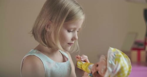 Porträt eines lächelnden kaukasischen Mädchens, das drinnen mit der Puppe spielt