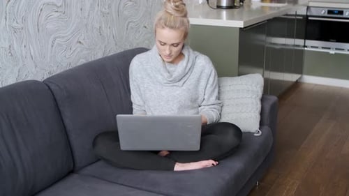 Woman Works on Laptop While Sitting on Sofa