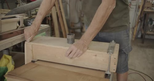 Adult working on a wooden machine with screws