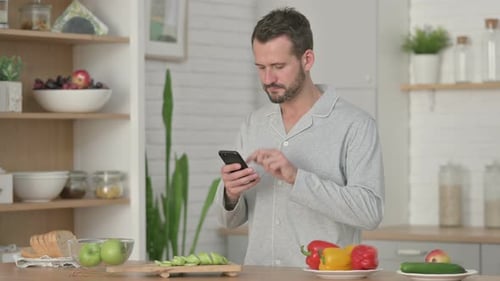 Man Using Smartphone Near Kitchen Counter at Home