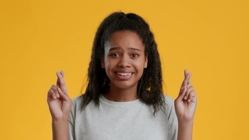 Young Woman with Fingers Crossed Hopes for Luck