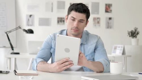 Man Using Tablet Device Looks Confused and Frustrated