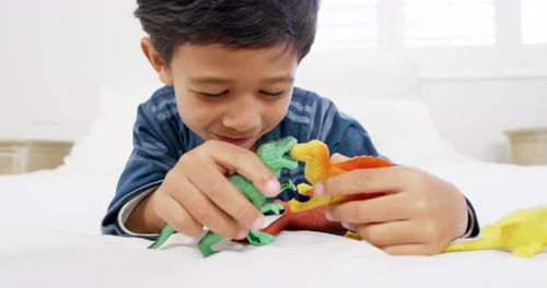 Boy Playing With Dinosaurs on a Bed
