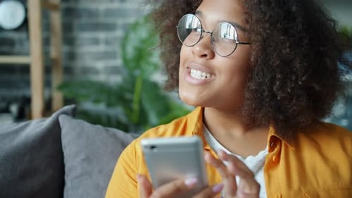 Happy African American Teenager Using Smartphone at Home Laughing