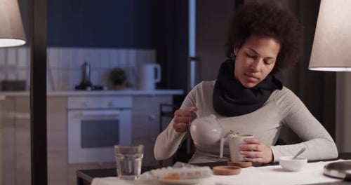 Woman Pours Tea in a Kitchen at Night