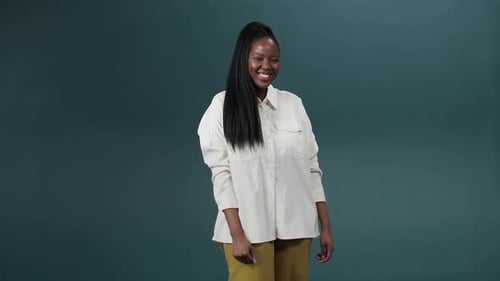 Beautiful Young Woman Posing Isolated and Broadly Smiling Over Green Wall Background