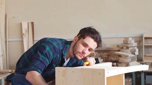Man Hammers Wood in Workshop