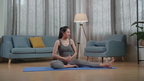 Woman Stretches and Talks on Yoga Mat