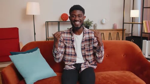 Cheerful Man Gesturing While Sitting on Couch Indoors