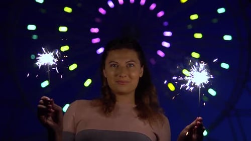 Smiling Woman Holding Sparklers at Night