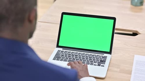 Man Works on Laptop with Green Screen