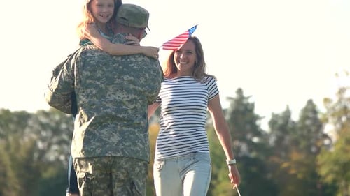 Soldier Reunited with His Family on a Sunny Day in the Park.