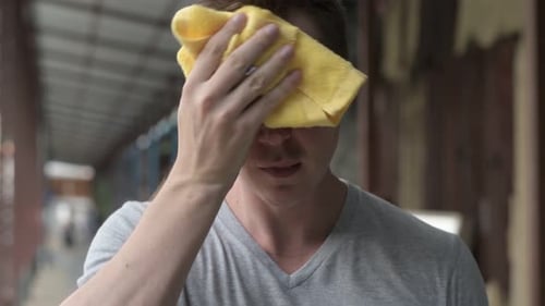 Young Tired and Exhausted Tourist Man Wiping Sweat and Using Phone at Pier