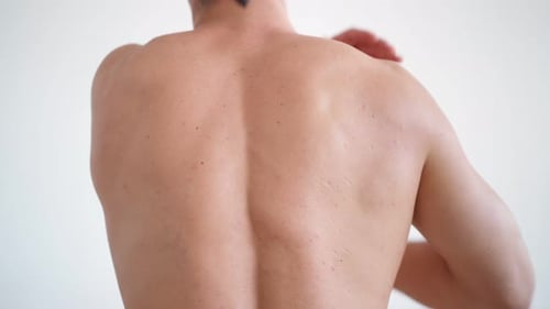 Muscular Man Reaches Arm Across Back and Shoulder