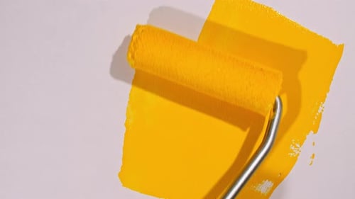 Paint Roller Applying Bright Yellow Paint Close Up