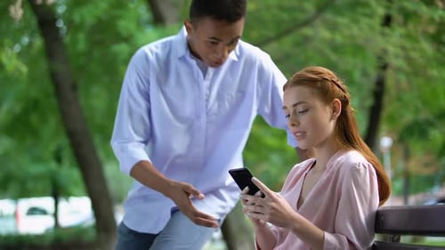 Afro-American Teen Boy Arguing With Girlfriend Chatting Smartphone, Jealousy