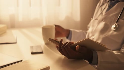 Doctor Reading Patient File in Office with Coffee