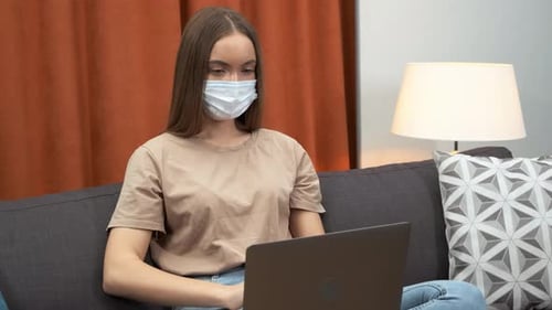 Woman with Mask Working on Laptop at Home