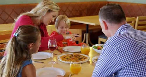 Family Enjoying Pizza Meal Together at Restaurant
