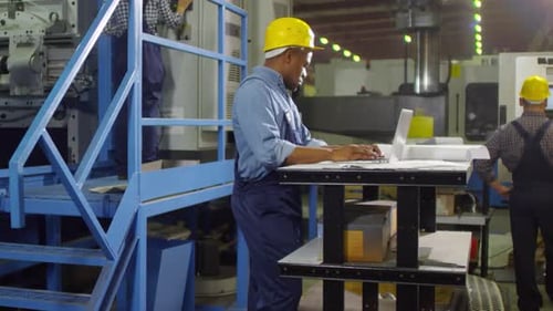 Black Engineer Writing Report on Laptop