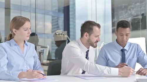 Middle Aged Businessman and His Assistants Discussing the Documents in Office