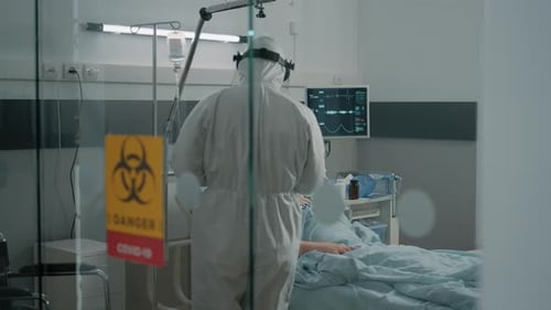 Patient Lying in Bed with Doctor in Hazmat Suit