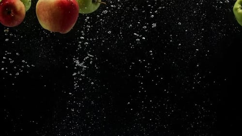 Äpfel unter Wasser. Frische Äpfel fallen ins Wasser auf schwarzem Hintergrund
