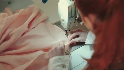 The Tailor Sewing Clothes in Atelier with Sewing Machine.
