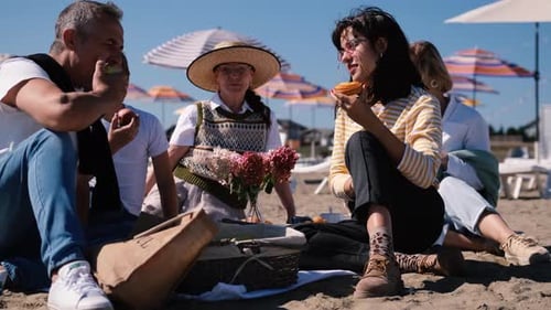 Happy Family with Children and Older Generation Relaxing on the Beach and Eating Vegetables and