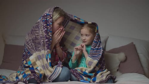 Young Adult and Child Talking Under Blanket