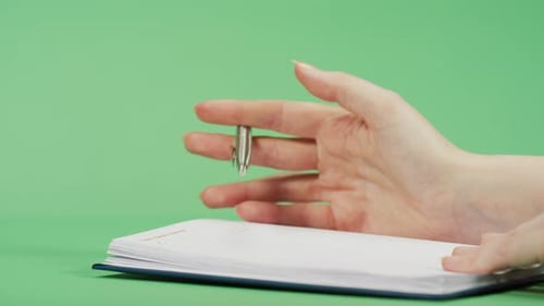 Hand Holding Pen Over Open Notebook
