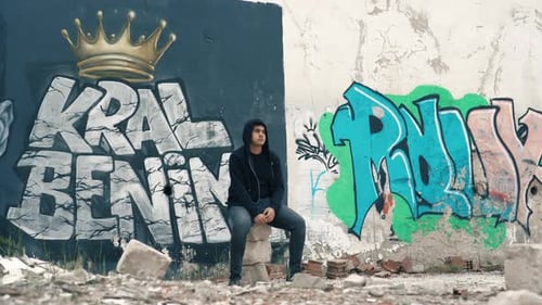 Álcool e jovem na frente da parede pintada de grafite.