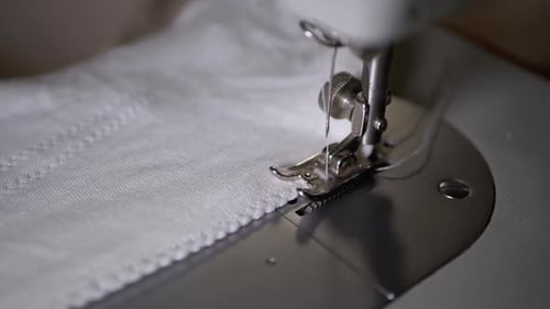 Nahaufnahme einer Nähmaschinennadel mit Faden durchbohrt Stoff in Zeitlupe