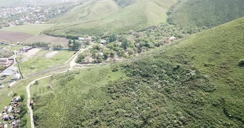 Scenic Aerial View of Paraglider Flying Over Green Hills