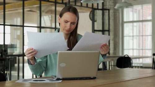 Eine wütende Frau, die Probleme hat, wirft Papierdokumente, während sie an einem Projekt arbeitet