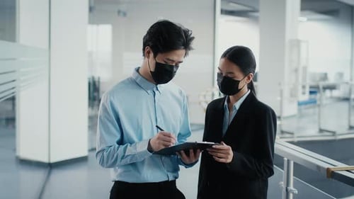 Asian Coworkers Discussing Work Wearing Face Masks In Office
